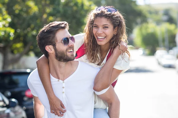 Hip man giving piggy back to his girlfriend