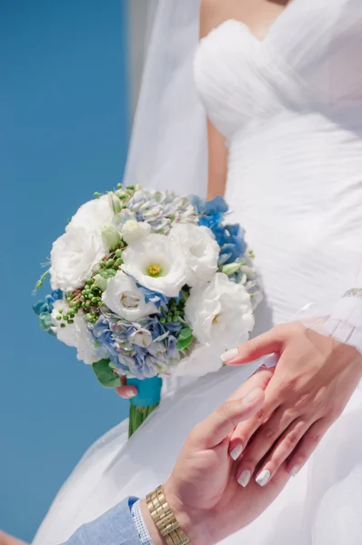 Hands with wedding rings and beautiful wedding bouquet