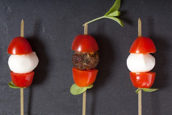 Small snacks canape with cherry tomatoes, mozzarella and meatbol