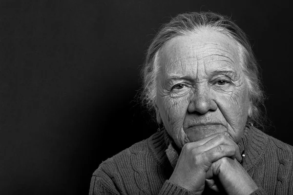 Portrait of elderly woman on dark background. Toned