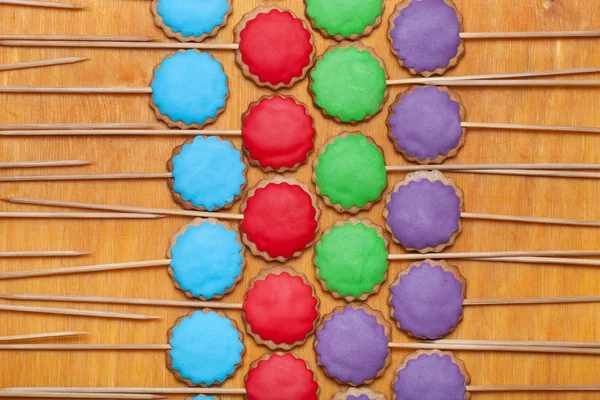 Gingerbread cookies with colored mastic on sticks on the old woo