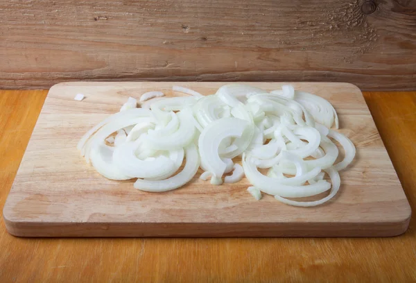 Chopped fresh onion on an light wooden cutting board on a old wo