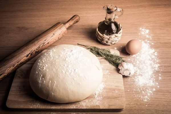 Dough on a board with flour. olive oil, eggs, rolling pin, garli