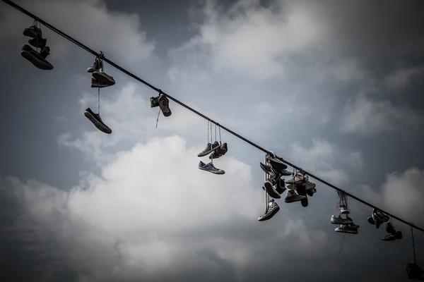 Old Shoes hanging on electrical wire against a blue sky