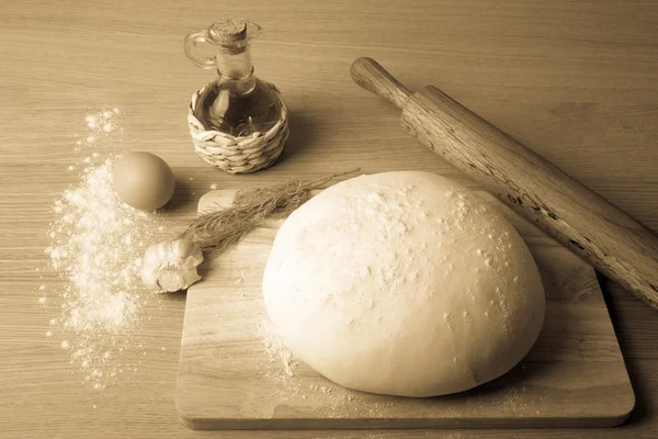 Dough on a board with flour. olive oil, eggs, rolling pin, garli