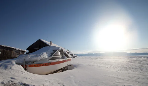 Old ship and wooden house on the ice of  Lake Baykal