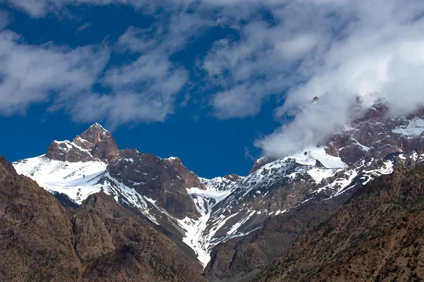 Clouds over the snow-covered tops of the rocks. Landscape