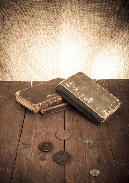 Vintage books and coins and spectacles on old wooden table. Tone