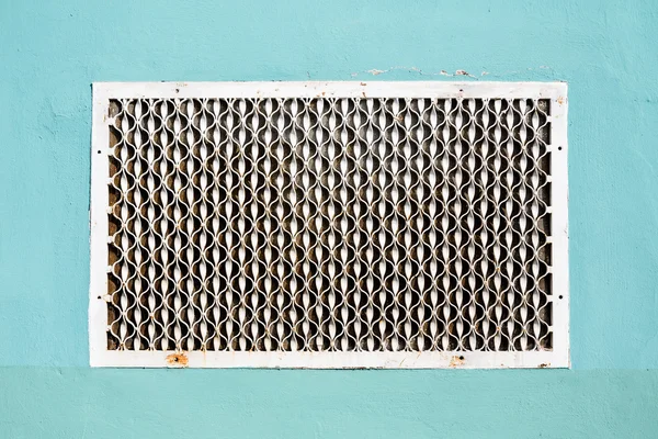 Old metal patterned ventilation grid on the plastered wall