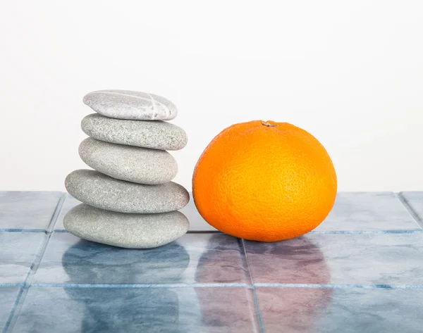 Stack of stones for spa procedures and orange on a table made of