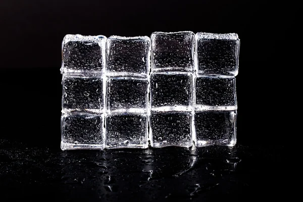 Wall of Ice cubes on black wet table. Selective focus