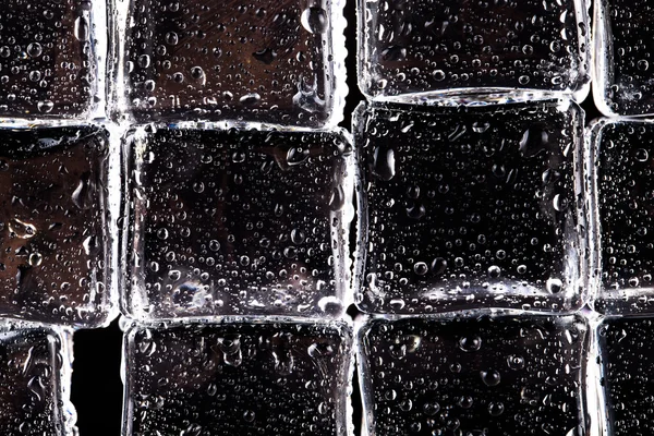 Wall of wet Ice cubes on black background. Selective focus