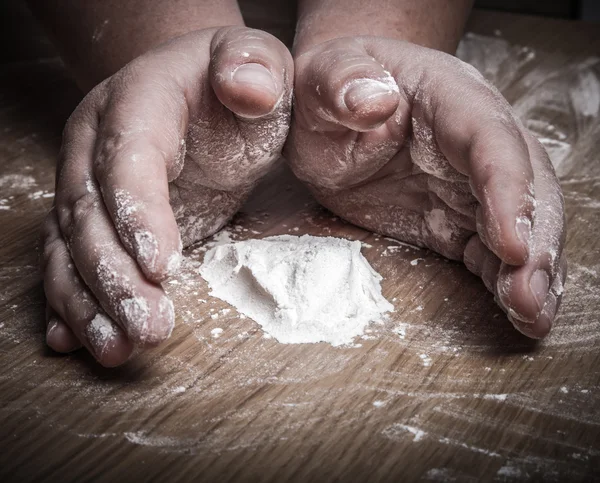 Flour on light wooden table like background with womans hand. Se