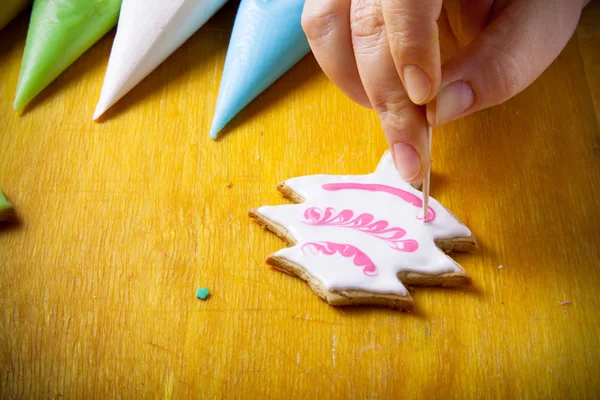 Woman\'s hands in process of drawing on new year gingerbread cook
