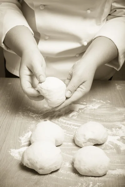 Female hands cut up dough. Selective focus. Toned