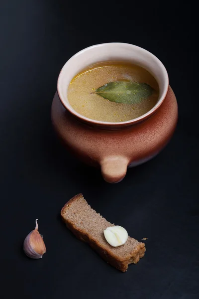 Rice soup in a clay pot on a black table or background