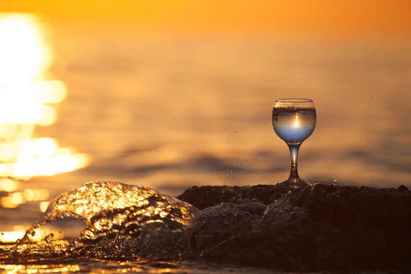 Glass of white vine with reflections of sun and sea on the backg