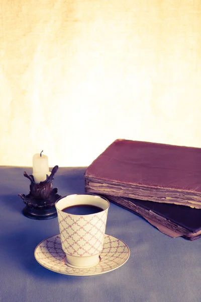 Old books, cup of coffee, candy and ancient candle on the table.