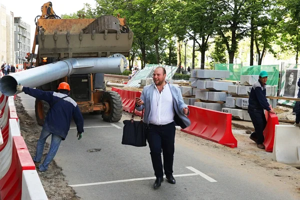 MOSCOW, RUSSIA - MAY 15, 2016: Laughing man with a smartphone and a black bag on a construction site. Reconstruction of the roadway within the city beautification program My Street in Moscow.