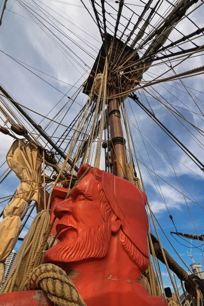 Carved head of sailor painted in orange red and rigging ropes of Tall Ship HMB Endeavour at Darling Harbour in Sydney