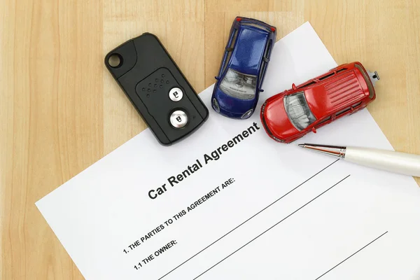 Car rental agreement, remote car key, a pen and mini car models