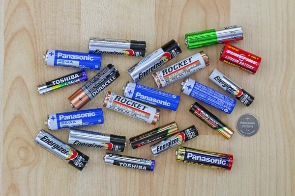 Primary cell and rechargeable battery from different brands on a wooden background