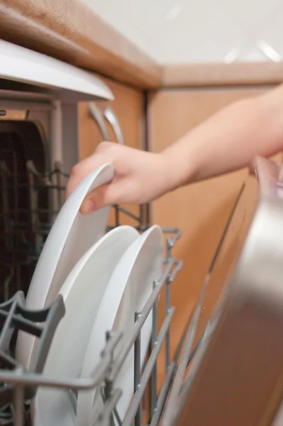 Child\'s hand put plate in dishwasher
