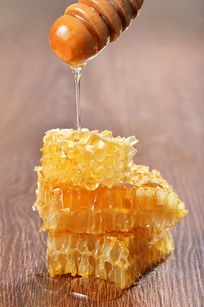 Honey dripping on honeycombs on wooden background