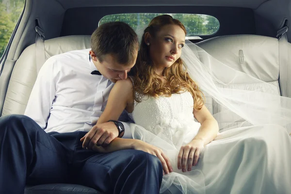 Bride and groom kissing in limousine on wedding-day