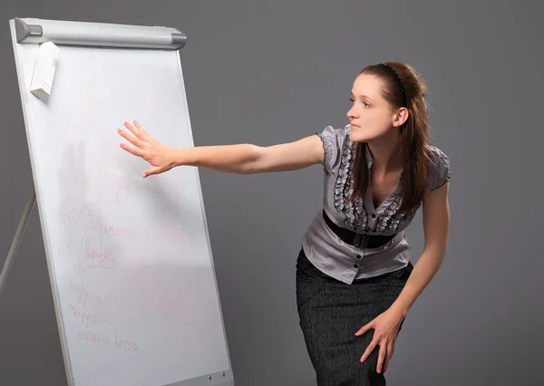 Young businesswoman standing next to flip board and pointing hand