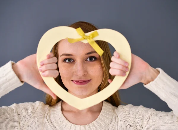 Closeup portrait of young female holding heart shape isolated on gray background