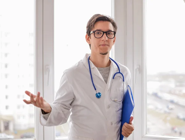 Male Doctor standing with folder near window