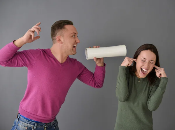 Man talking through  tube and a woman plugging her ears