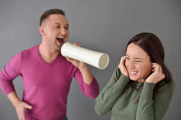 Man talking through  tube and a woman plugging her ears