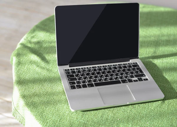 Laptop computer on the desk with green tablecloth