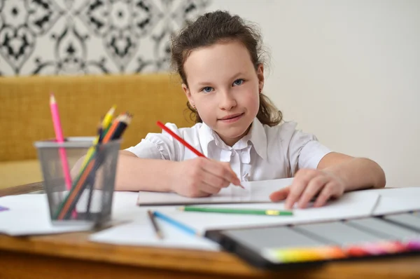 Little girl drawing picture in a sketchbook with colored pencils