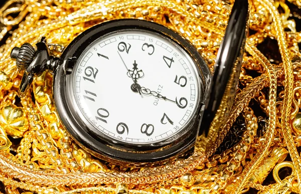 Pocket watch with pile of various golden jewelry, isolated black