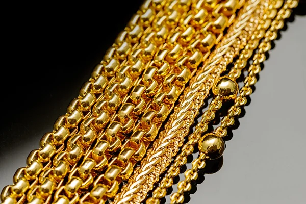 Closeup gold chain necklaces over black background