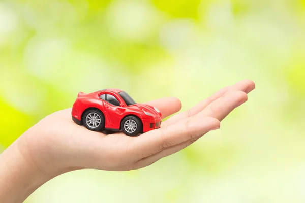 Hand holding the model of car on green background. symbol photo