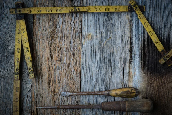 Old Tape Measure and Screwdriver for Construction on Rustic Wood