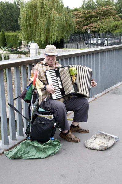 PARIS - August 13: Unidentified senior musician play accordion on the bridge on August 13, 2013 in Paris, France. Dozens buskers perform on the streets and in the metro of Paris.