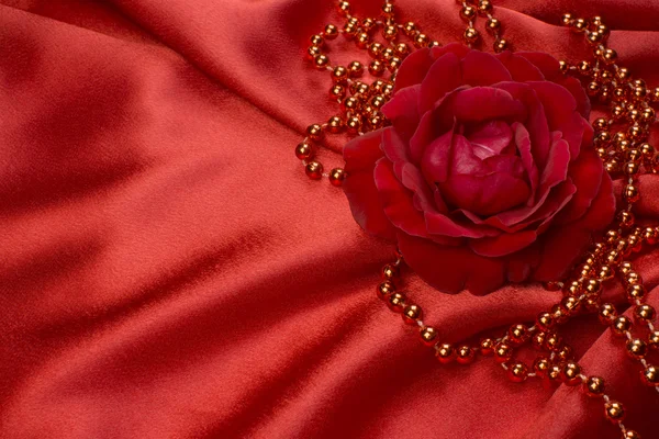 Red rose and pearls on satin