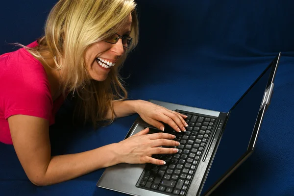 Smiling woman types on laptop