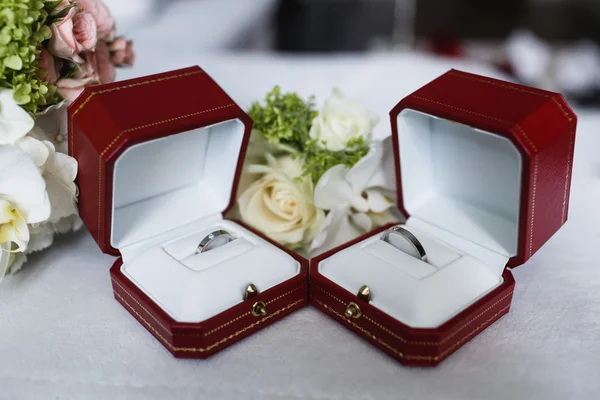 Wedding rings in a box near a wedding bouquet