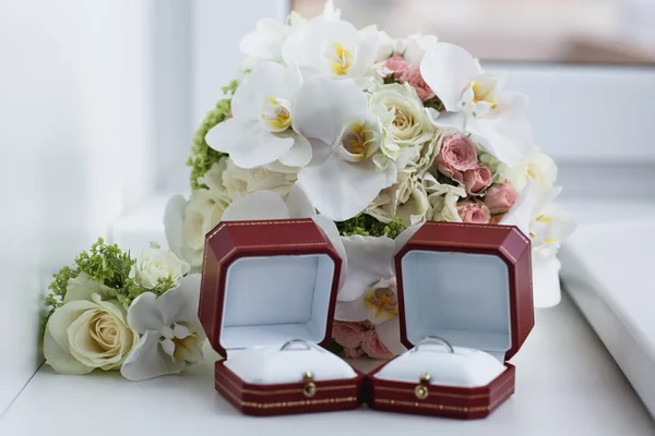 Wedding rings in a box near a wedding bouquet