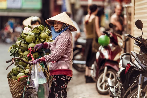 HO CHI MINH, VIETNAM - JAN 15, 2016: the Vietnamese woman sells cocoes on the street in Hochiminh (Saigon) on the sunset. Saigon is the largest city in Vietnam