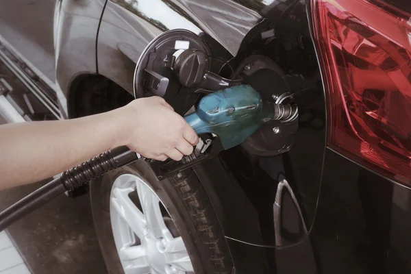 Hand refilling the car with fuel.