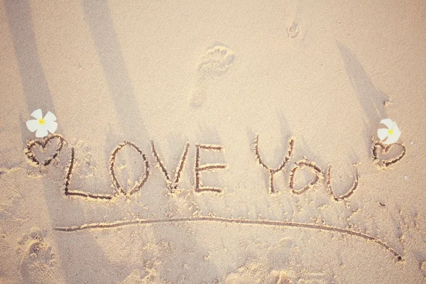 The word love you written in sand on beach