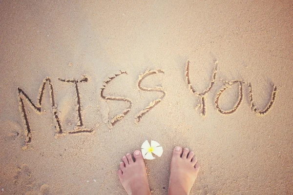 Selfie of word miss you written in sand on beach