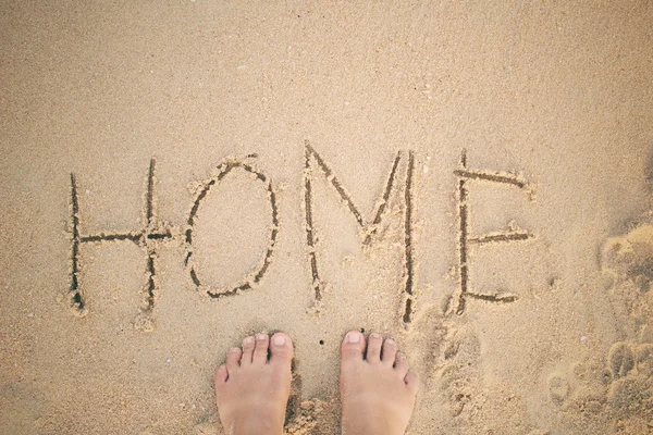 Selfie of word home written in sand on beach